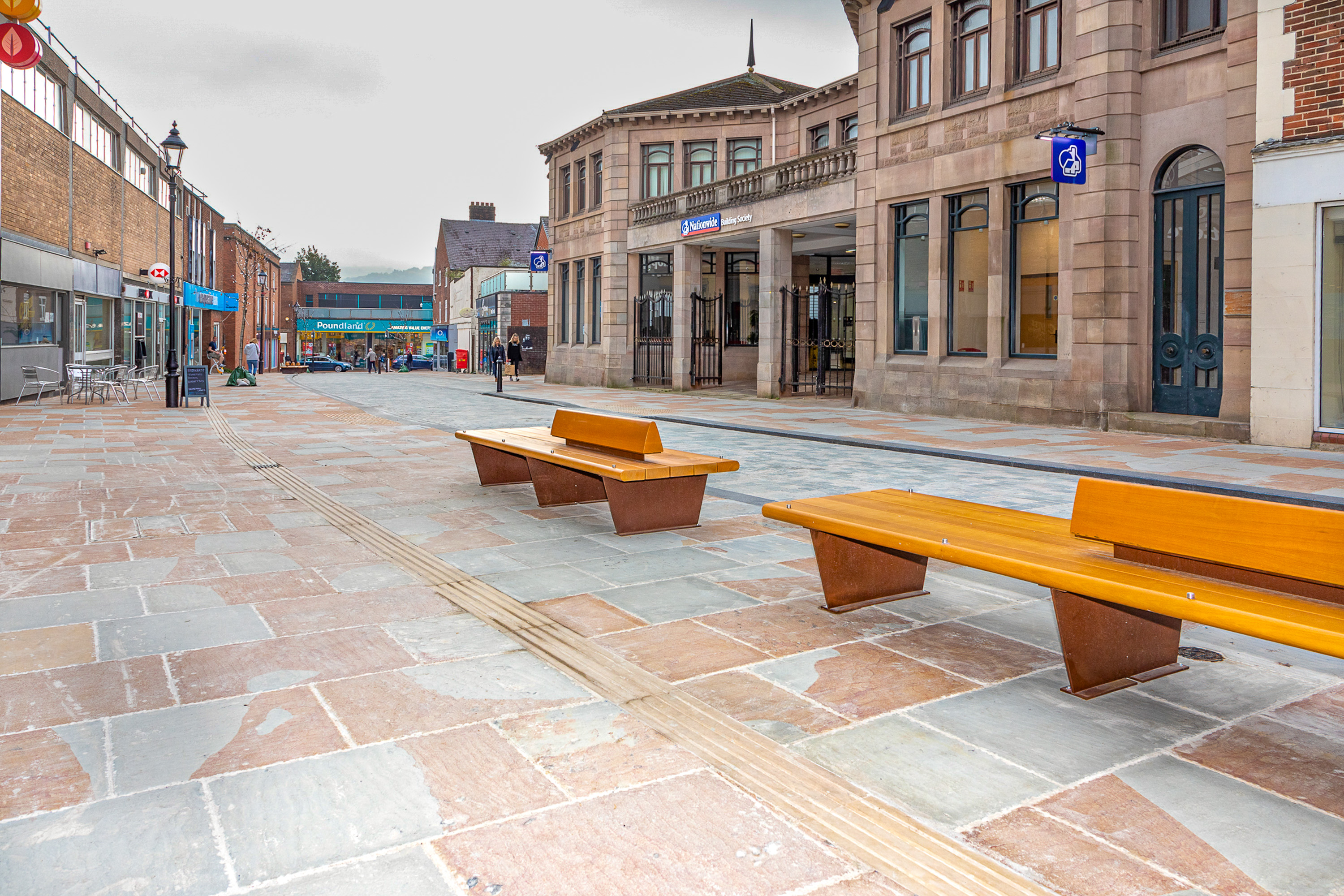 Completed public streetscape with pedestrian paving, seating and surrounding buildings.