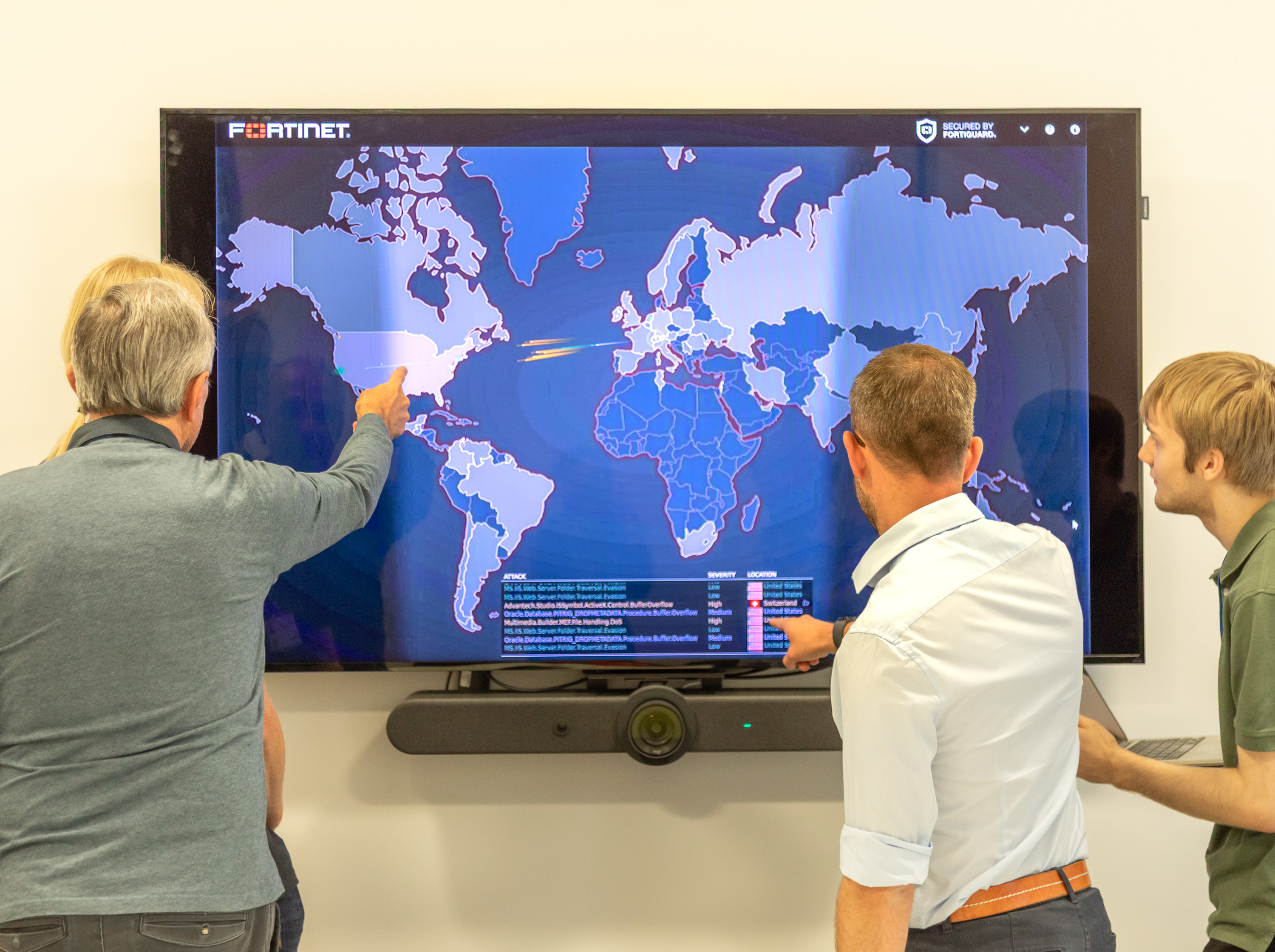 IT team reviewing live cyber security digital mapping network data displayed on large interactive screen at Ringway Jacobs head office